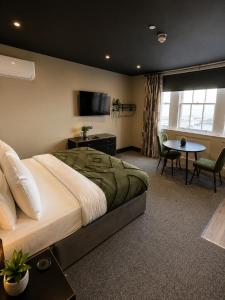 a bedroom with a bed and a table and a tv at The Clyffe Hotel in Lowestoft