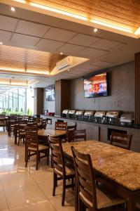 a restaurant with tables and chairs and a tv on the wall at Hotel Crown Victoria in Querétaro