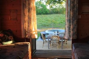 a room with a table and chairs on a porch at roulotte de charme avec jacuzzi privé in Beaupouyet