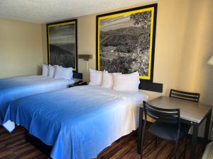 a hotel room with two beds and a table and a desk at Super 8 by Wyndham Lumberton NC in Lumberton