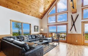 a living room with a leather couch and large windows at Pinecone Manor Beech Mountain in Beech Mountain