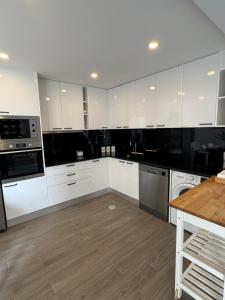 a kitchen with white cabinets and a wooden floor at Refúgio da Barra in Gafanha da Nazaré