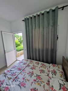 a bedroom with a bed and a window with a curtain at Sunset Panorama Residence in Vlorë