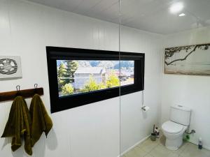 a bathroom with a shower with a window and a toilet at The Cozy Cottage-With elevated views in Queenstown