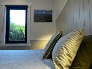 a bedroom with a bed with two pillows and a window at The Cozy Cottage-With elevated views in Queenstown