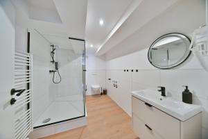 a white bathroom with a shower and a sink at Hotel M&H Apartments - Salzgitter in Salzgitter