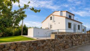 a white house behind a stone wall at O Retiro da Costa Galitrips in Muxia