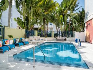 a swimming pool with chairs and palm trees at voco Sarasota by IHG in Sarasota