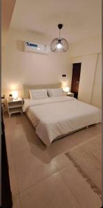 a large white bed in a room with two tables at غرفتين وصالة شقق ديما الفندقية in Abha