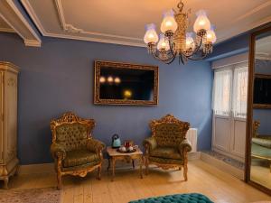 a room with two chairs and a table and a chandelier at Hostal Boutique Puerta del Sol in Torrelavega +46 photos