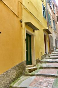 an alley with a yellow building with a green door at Mezza Galea in Vernazza