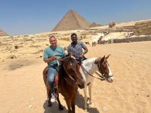 two men riding a horse in front of the pyramids at Farida Pyramids inn& Jacuzzi in Cairo