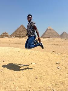 a man kneeling on the ground in front of pyramids at Farida Pyramids inn& Jacuzzi in Cairo