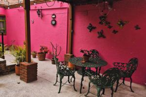 a table and chairs in front of a pink wall at Casa Manzanos in Guanajuato