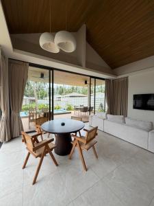 a living room with a table and chairs and a couch at Wave Villa New 2BR Pool Villa in Ko Phangan