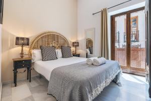 a bedroom with a large white bed and a window at BnS Dauro Suites in Granada