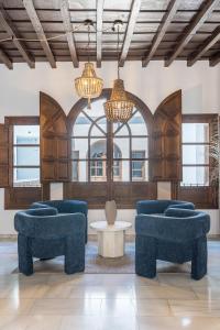a lobby with blue chairs and a table and chandeliers at BnS Dauro Suites in Granada