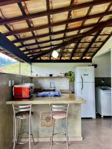 a kitchen with a counter with two stools and a refrigerator at Casa Cambuí Hospedagem Rural in São José do Rio Preto +65 photos