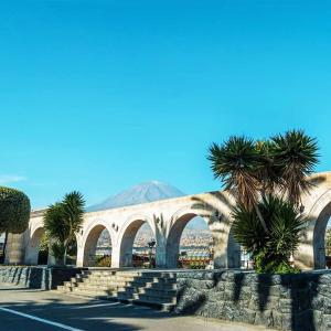 a building with palm trees and a mountain in the background at Hospedaje Totocha Yanahuara Arequipa in Yanahuara