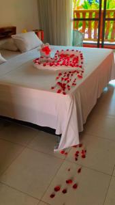 a bed with red rose petals on the floor at Pousada recanto nordestino in Caucaia