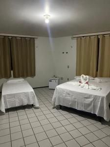 a bedroom with two beds with white sheets at Pousada recanto nordestino in Caucaia