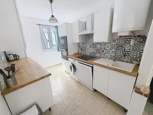 a kitchen with white cabinets and a washer at Charmant in Saint-Martin-Vésubie