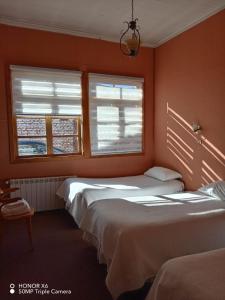 two beds in a room with orange walls and windows at ayelen bed and breakfast in Punta Arenas