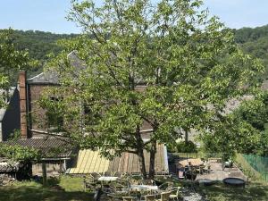 a tree with tables and chairs in front of a house at La Tulipe in Vireux-Molhain