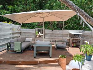 a patio with an umbrella and chairs and a table at Villa Lola- Au cœur de la BO - 100m de la plage, cuve 800L in Orient Bay