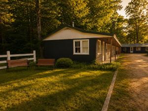 a small black building with a bench in front of it at Lakeside Heritage Resort in Carp Lake