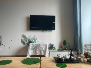 a living room with a table and a tv on the wall at Canary Nest Solforest Ecopark Homestay in Kim Quan