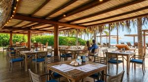 a couple sitting at a restaurant with tables and chairs at Residences at Las Palmas in Zihuatanejo
