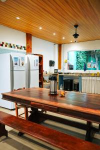 a large kitchen with a wooden table and refrigerator at Sea Wolf Surf Hostel Campeche in Florianópolis