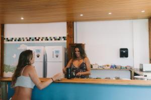 a woman in a kitchen talking to a woman in a mirror at Sea Wolf Surf Hostel Campeche in Florianópolis