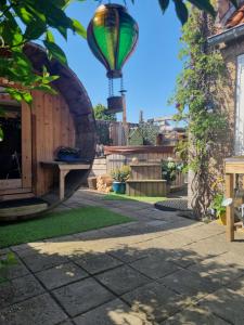a hot air balloon flying over a garden with a bench at Bleij-en-meer, 2 accommodaties, waaronder een 4p huisje en een heel klein gezellig Tiny-Wellness huisje voor 2p met sauna en heerlijke hottub, ook samen te huur voor een gezellig combinatie in Zoutelande