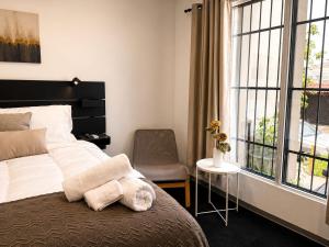 a bedroom with a bed and a chair and a window at Hostal Boutique Zona Rosa - San Benito in San Salvador