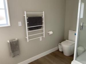 a white bathroom with a toilet and a towel rack at Fletcher House Sleeps 18 Location Views in Taupo