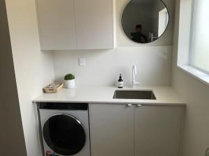 a kitchen with a washing machine and a mirror at Fletcher House Sleeps 18 Location Views in Taupo