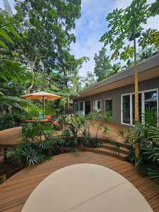 a wooden deck with an umbrella and a house at Seven on the Hillside in Pacific Harbour