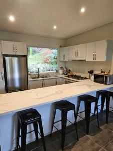 a kitchen with a large counter with four stools at Seven on the Hillside in Pacific Harbour +19 photos