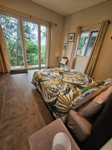 a bedroom with a bed and a large window at Seven on the Hillside in Pacific Harbour