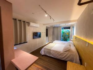 a bedroom with a bed and a window at Villa'l Mare Hotel in Maresias