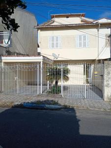 a dog standing behind a fence in front of a house at Morada Santa Rita in Aparecida