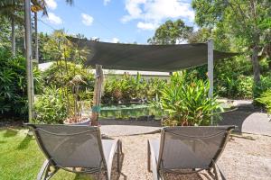 two chairs and a canopy in a garden at Stylish Tropical Villa with Lagoon Pool in Port Douglas +3 photos