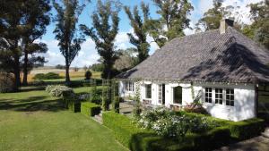 a small white cottage with a thatched roof at Estancia Ave María in Tandil
