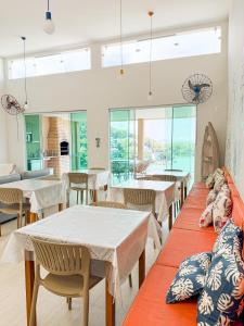 a dining room with tables and chairs and windows at Pousada Casa da Praia Angra in Angra dos Reis