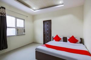 a bedroom with a bed with red pillows and a window at Super Hotel O Viraj Deluxe Narela in Delhi
