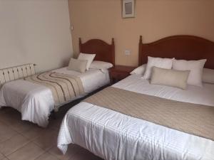a hotel room with two beds with white sheets at Hostal Avenida Pozo Alcón in Pozo Alcón
