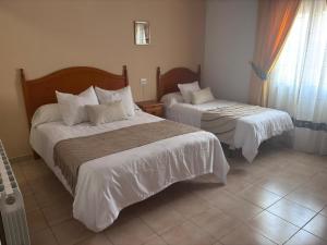 a hotel room with two beds and a window at Hostal Avenida Pozo Alcón in Pozo Alcón