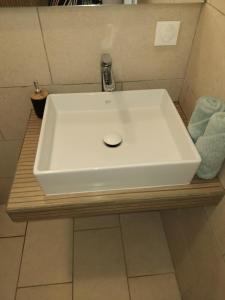 a white sink sitting on a wooden counter in a bathroom at Fare Zen Raiatea - with pool in Uturoa +6 photos